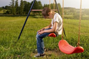 Boy looking sad on swing