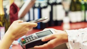 woman holding phone over payments device