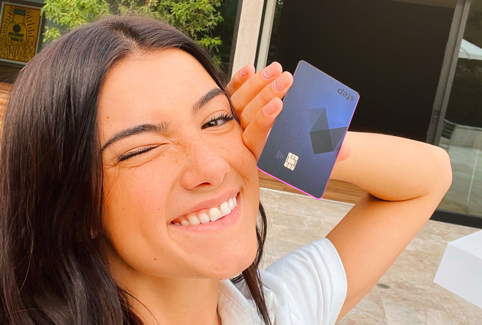 Chali D'Amelio holding a step card