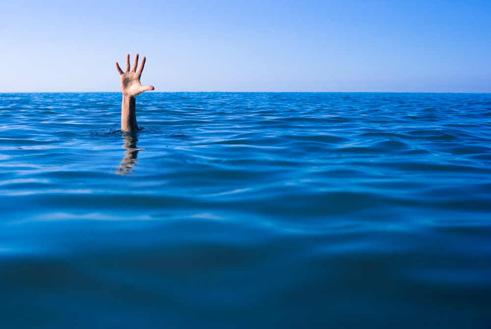 A human hand sticking up from the ocean.