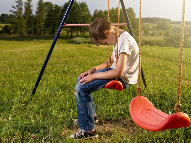 Boy looking sad on swing