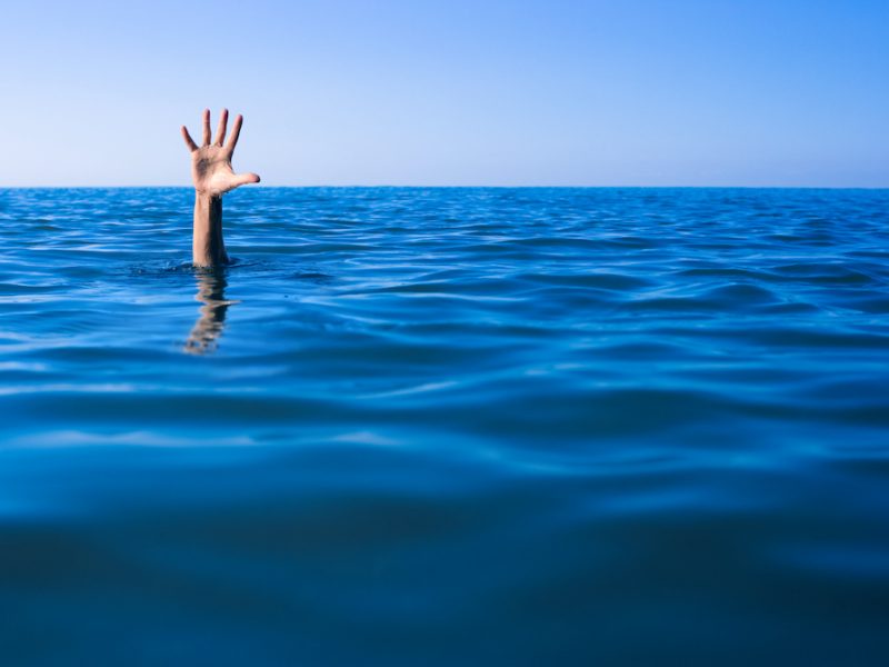 A human hand sticking up from the ocean.