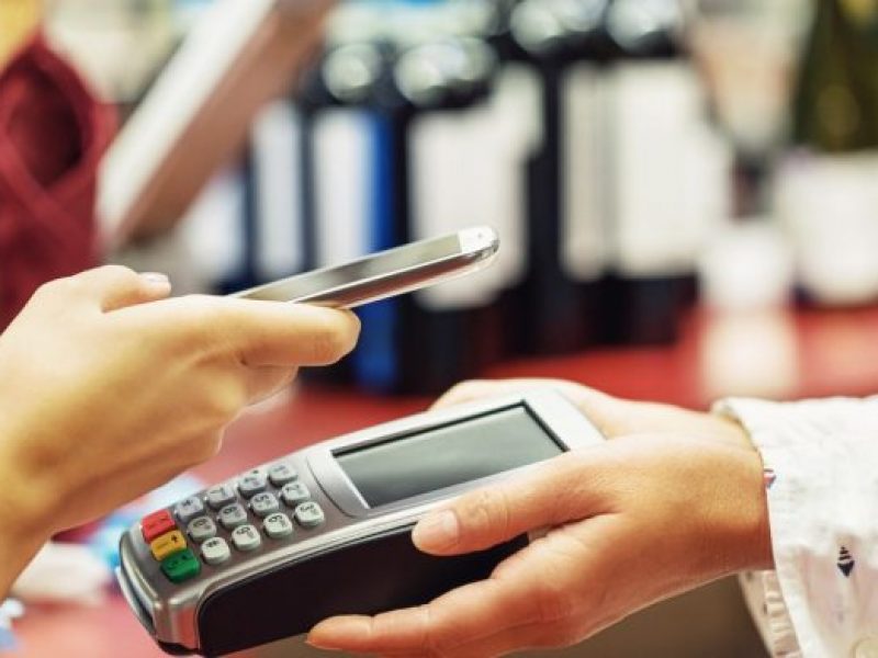 woman holding phone over payments device